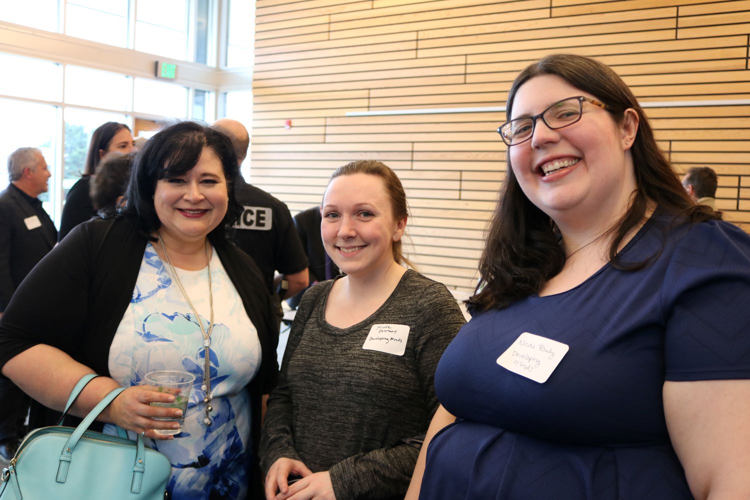 Three women smiling at camera at a networking event at Kenmore city hall in 2019