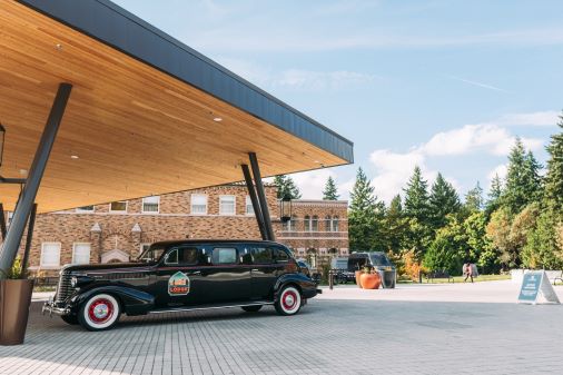 Black car parked under shelter in front of hotel building called The Lodge at St. Edward Park