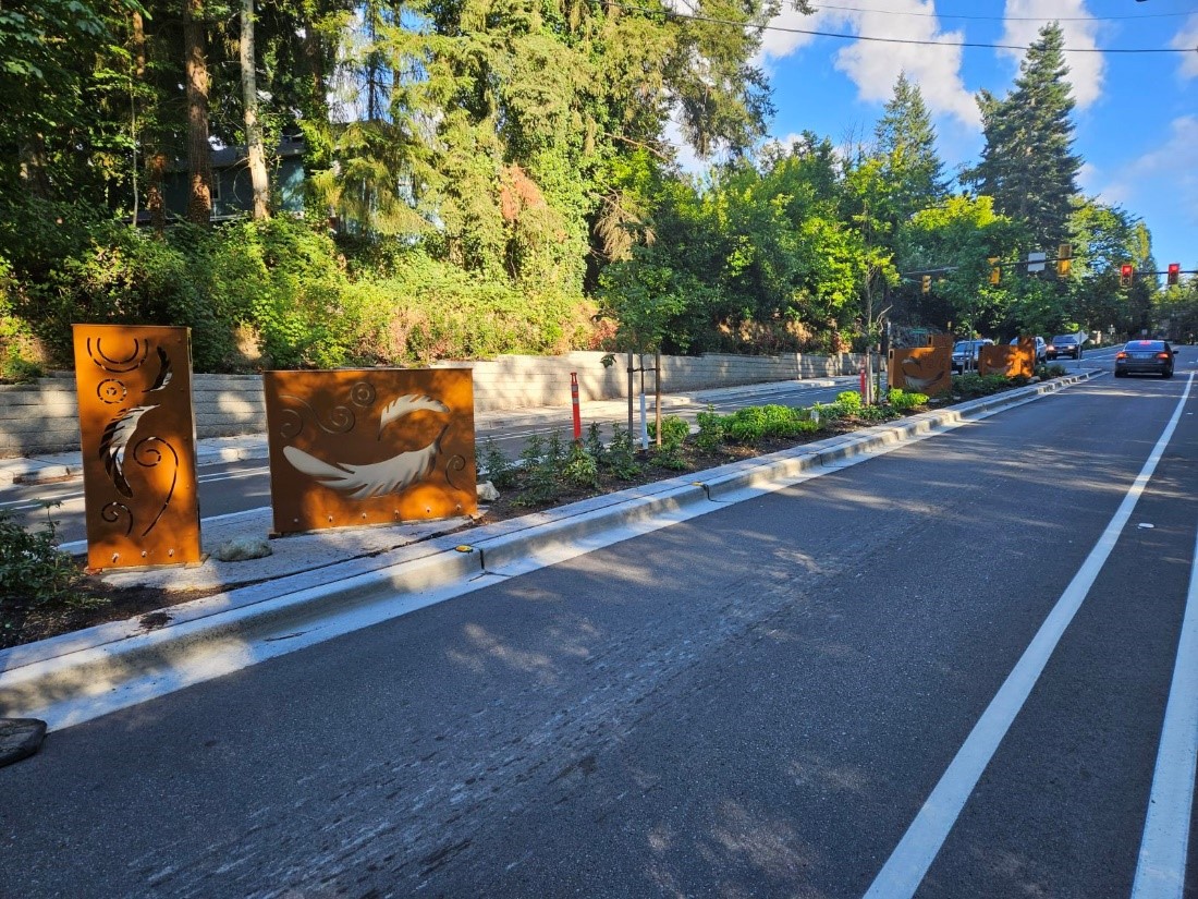 Metal sculpture with feather cut outs in the median of Juanita Way